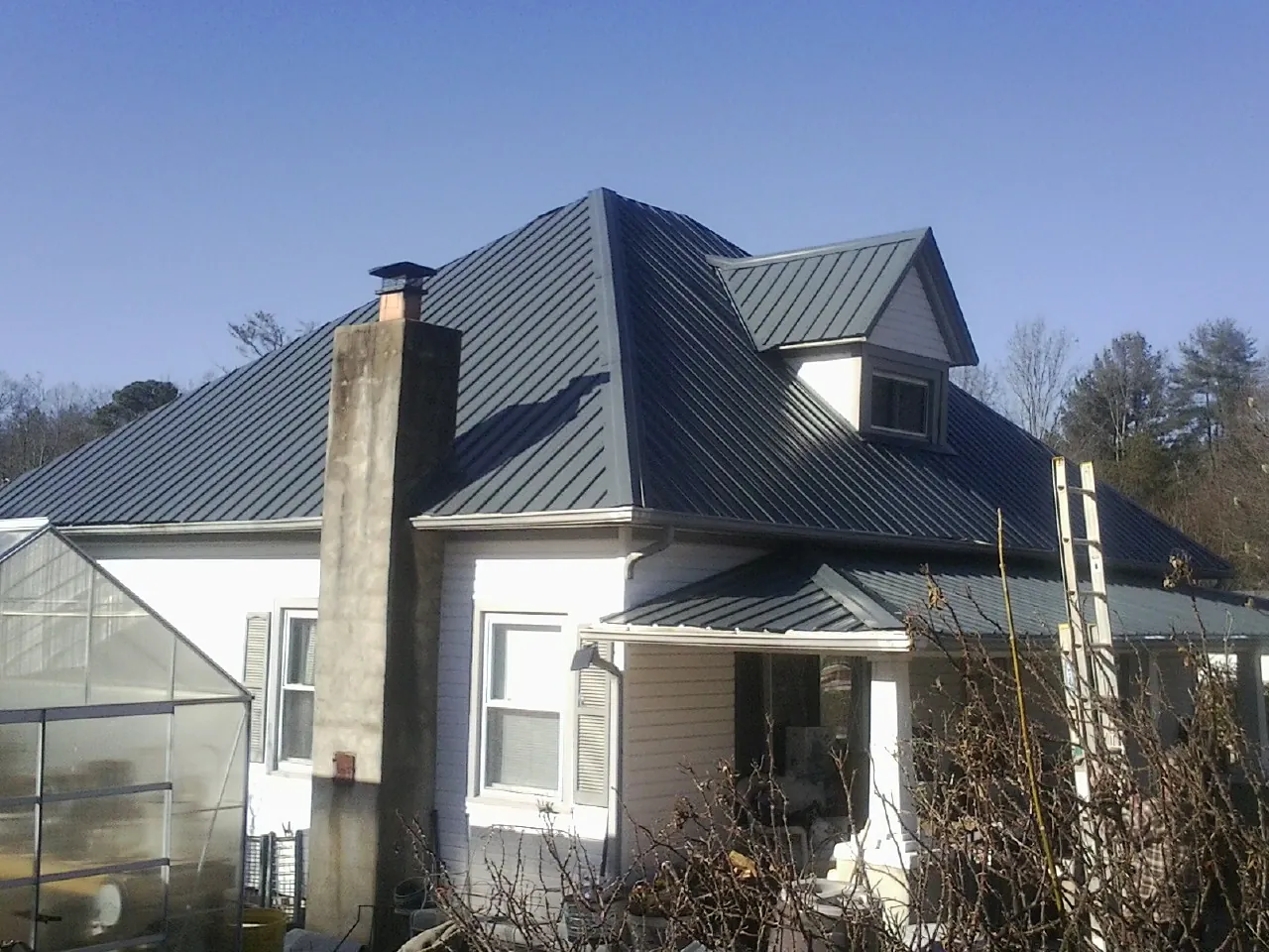 Dark blue standing seam metal roof on a white farmhouse with dormer — Slate & Tile Roof Repair by Roofing Brothers in Morley