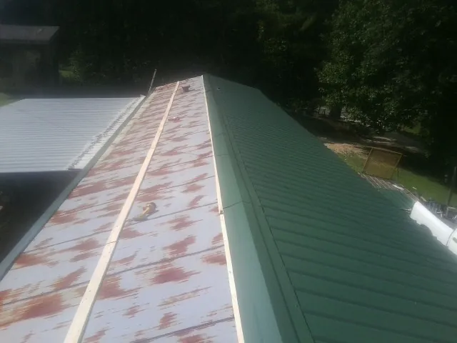 Old rusted panels beside newly installed green metal roofing — Wind Damage Roof Repair by Roofing Brothers in Morley
