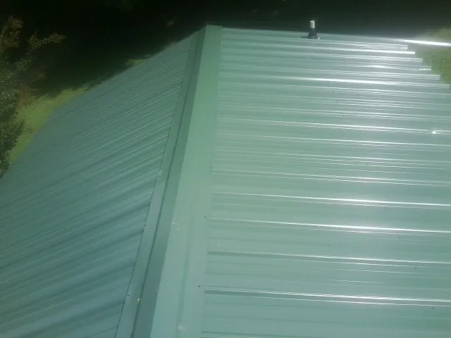 New green metal panels meeting at the ridge of a roof — Flat Roof Repair work by our crew in Morley
