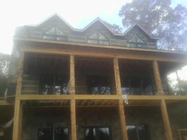 Dormers and porch framing on a large log home under construction — Roof Coating work by our crew in Morley
