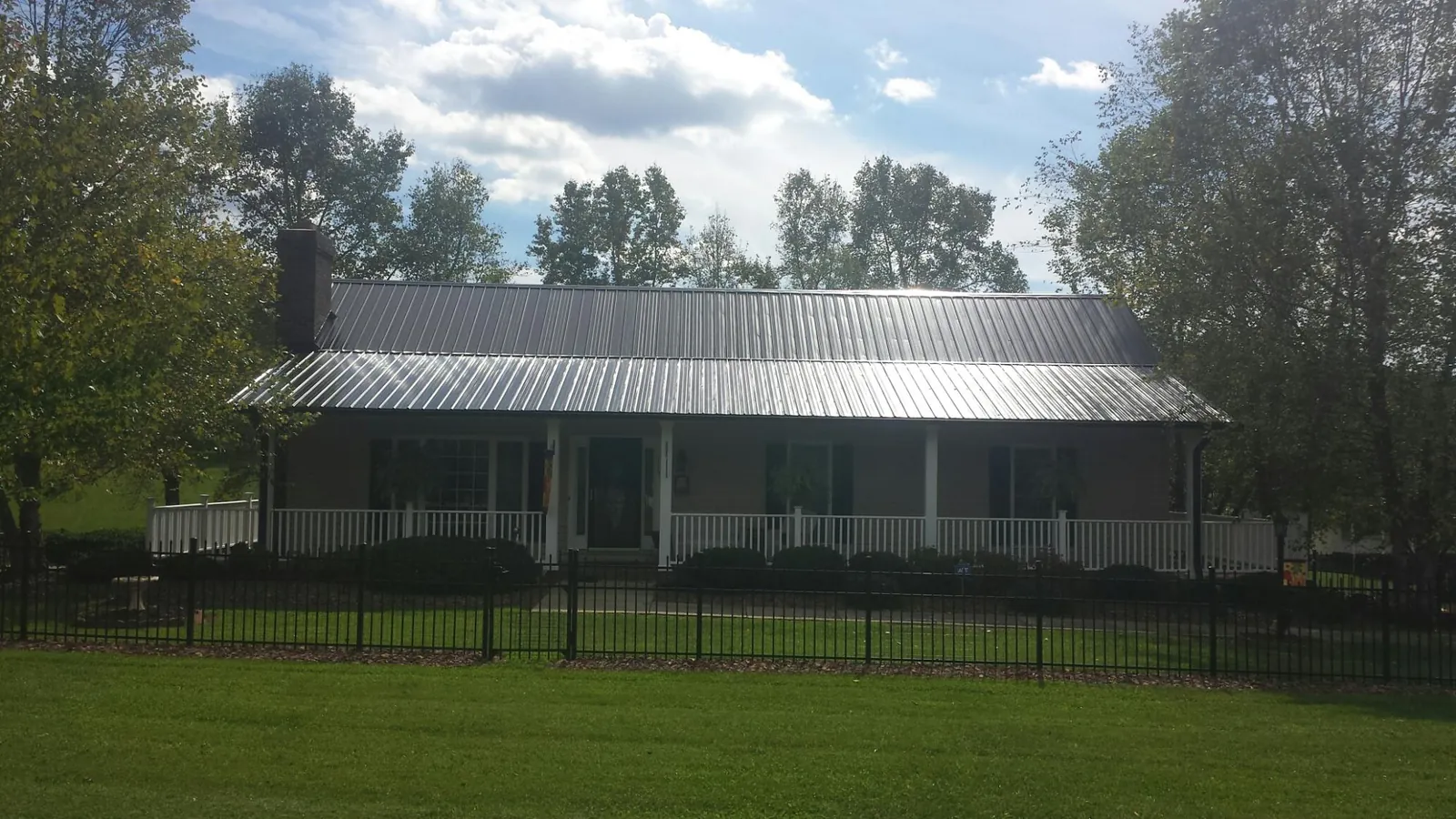 Gray metal roof on a brick ranch with a full width front porch — Gutter Guard Installation work by our crew in Morley