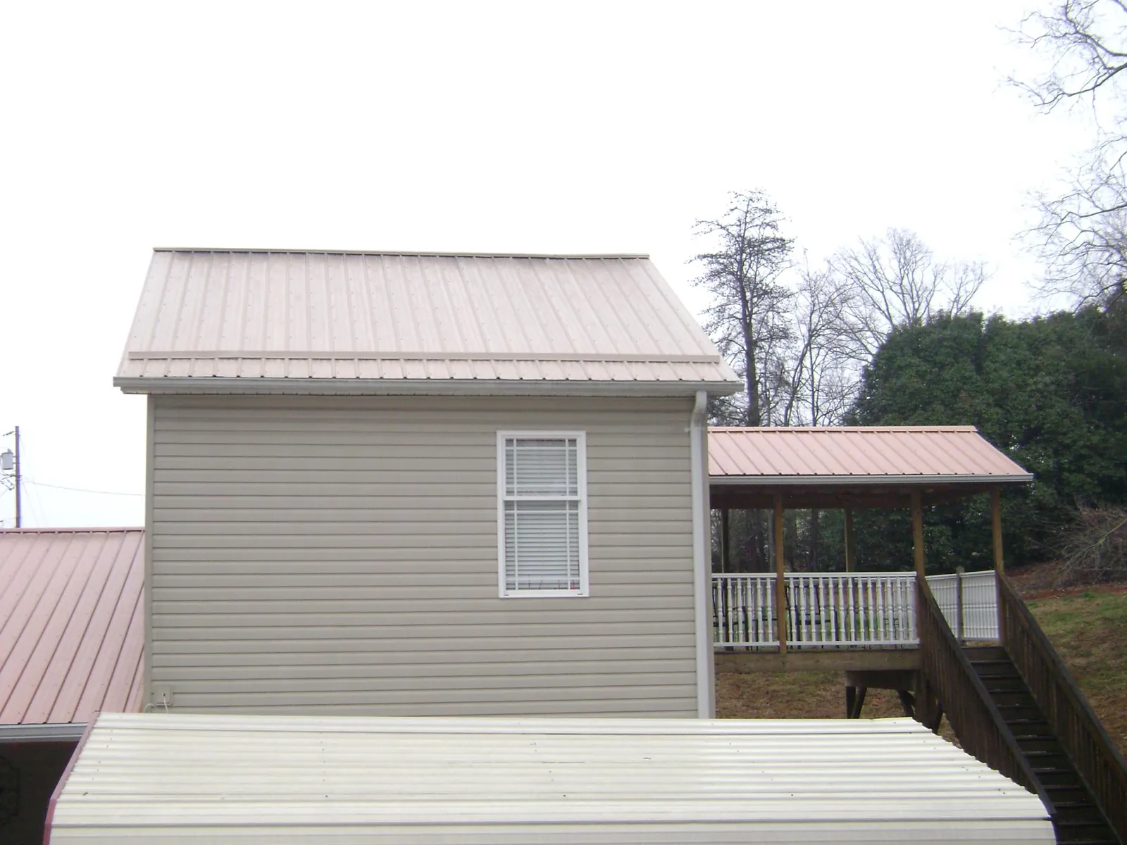 Tan metal roofs on a two story addition and attached porch, from a Roof Replacement job in Morley